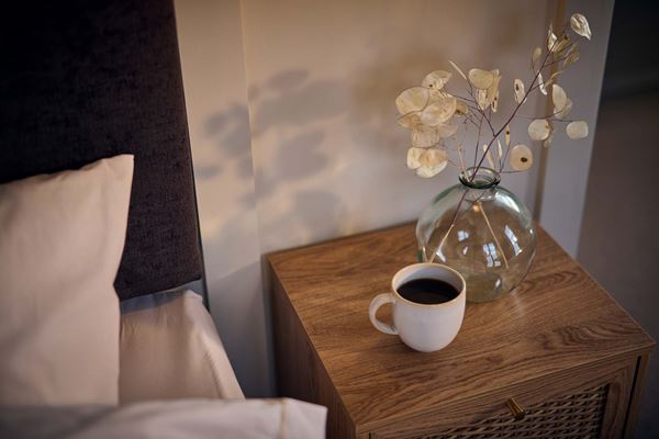Mug of coffee on bedside table in a modern bedroom.