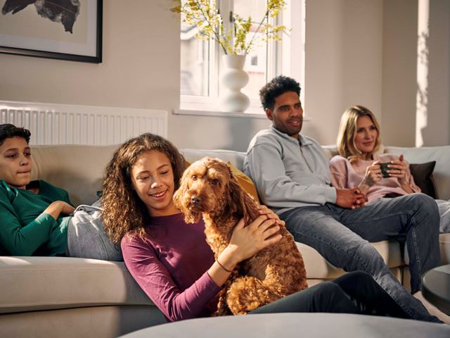 Family with cockerpoo dog in living room of Charles Church new home