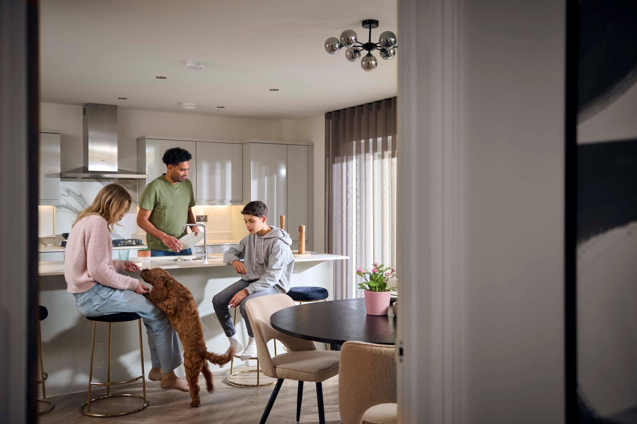 Parents and son with their dog in modern Charles Church kitchen
