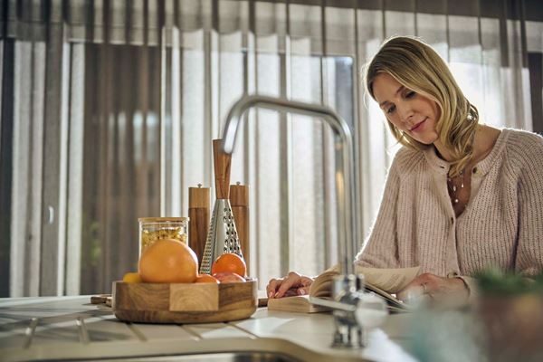 A blond woman sitting at a kitchen island reading a book. 