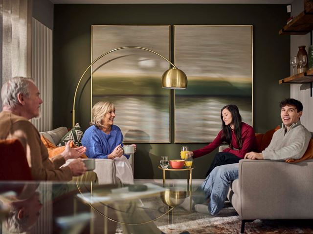 A young couple and parents socialising in a modern living room