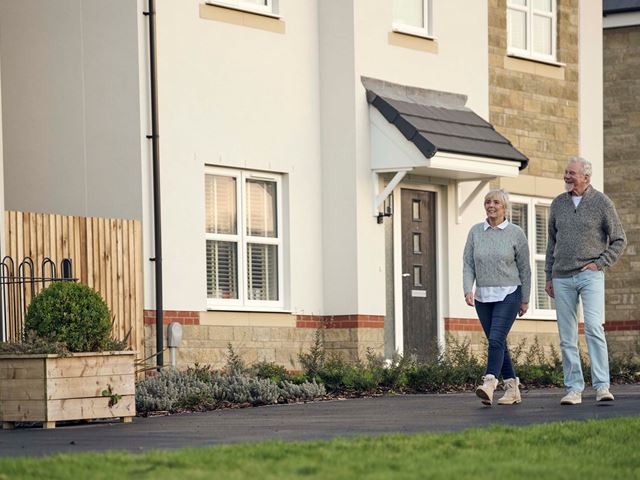 Downsizer older couple walking alongside new home for sale by Charles Church
