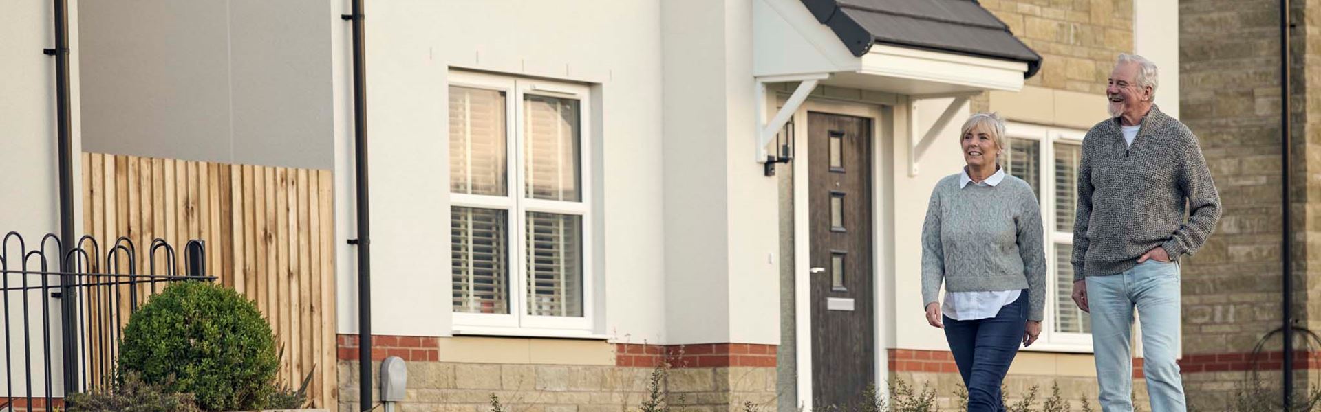 Downsizer older couple walking alongside new home for sale by Charles Church