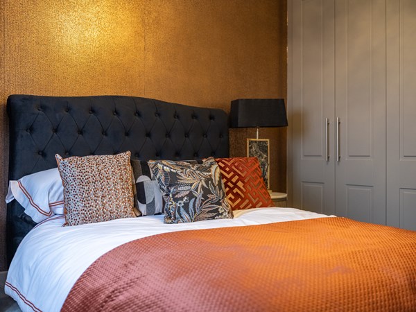 Bright gold textured wallpaper behind a double bed 