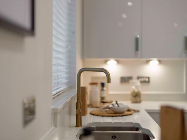 A close up of brass tap in a white new build kitchen